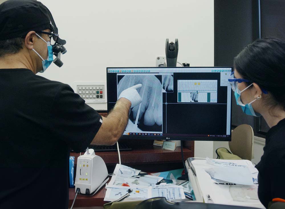 Dr. Javid reviewing digital dental X-rays with an assistant